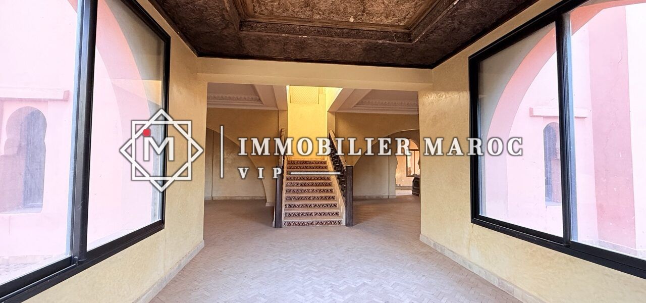 Salon avec plafond en bois sculpté et grandes fenêtres – riad à vendre Palmeraie Marrakech